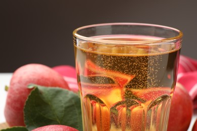 Photo of Fresh cider in glass and apples on table, closeup