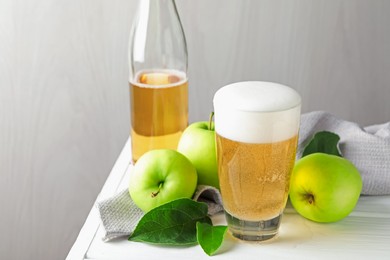 Photo of Fresh cider in glass, bottle and apples on white wooden table, closeup