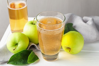 Photo of Fresh cider in glass, bottle and apples on white wooden table, closeup