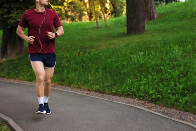 Photo of Athletic young man in sportswear running outdoors, closeup. Space for text