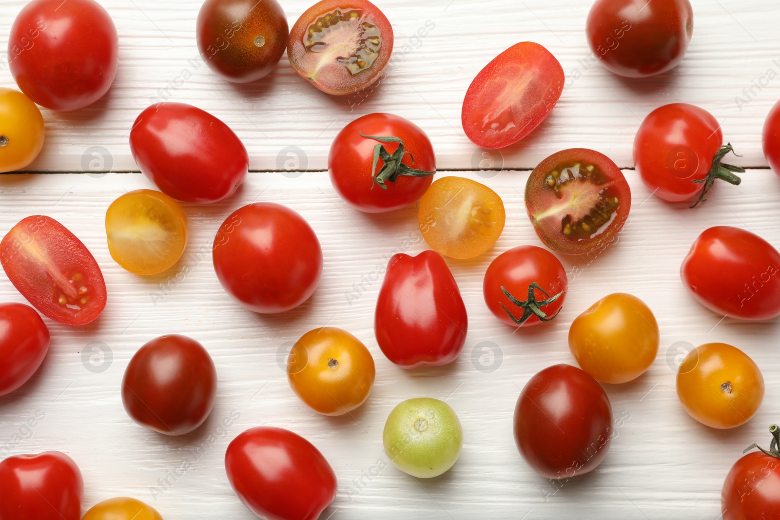 Photo of Different ripe tomatoes on white wooden table, flat lay