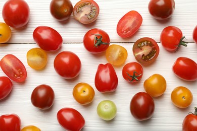 Photo of Different ripe tomatoes on white wooden table, flat lay