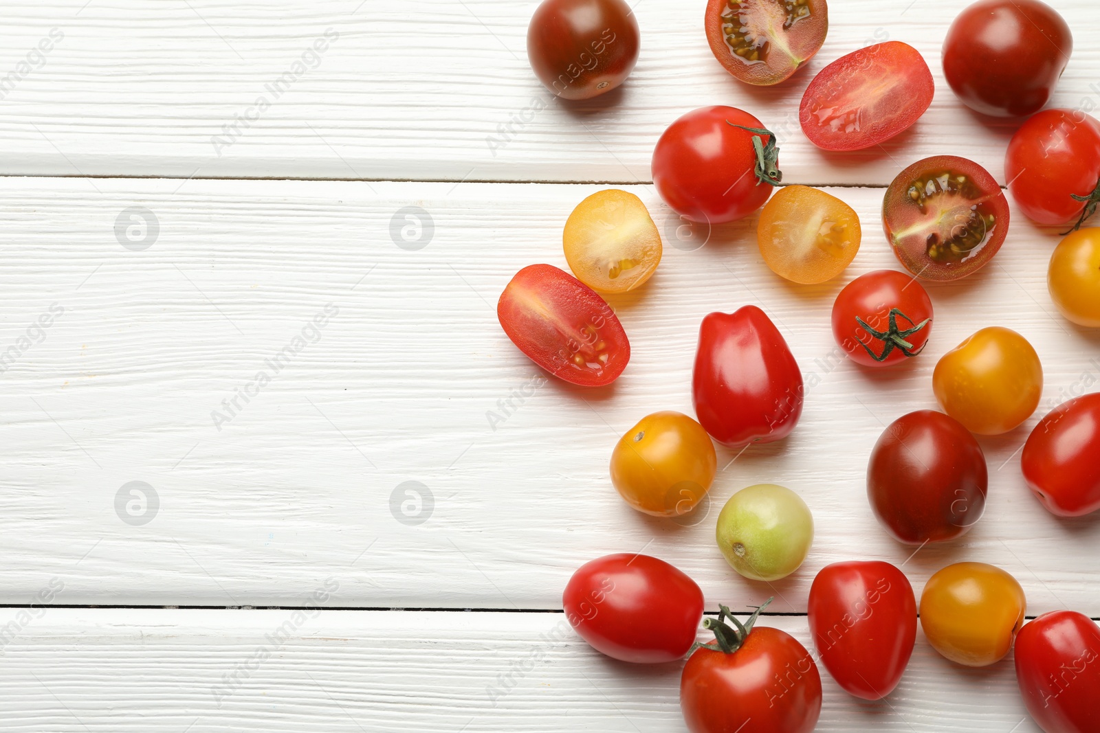 Photo of Different ripe tomatoes on white wooden table, flat lay. Space for text