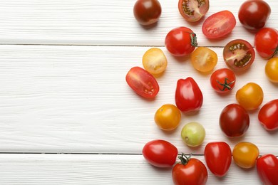 Photo of Different ripe tomatoes on white wooden table, flat lay. Space for text