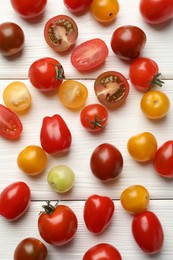 Photo of Different ripe tomatoes on white wooden table, flat lay
