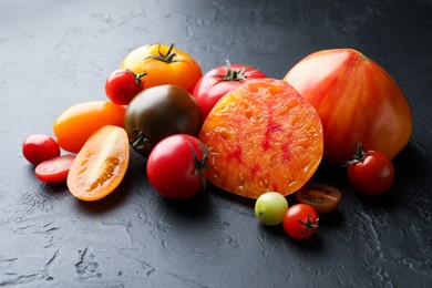 Photo of Different ripe tomatoes on black table, closeup