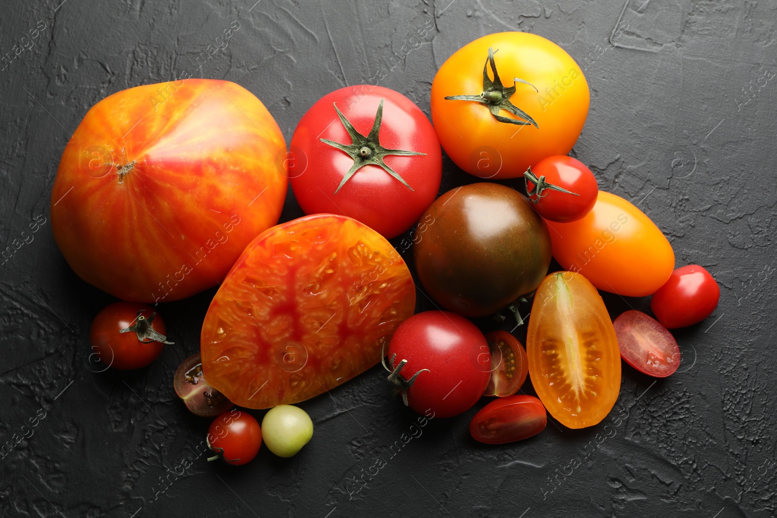Photo of Different ripe tomatoes on black table, flat lay