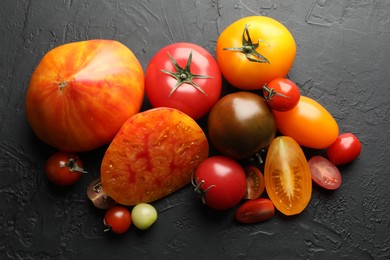 Photo of Different ripe tomatoes on black table, flat lay
