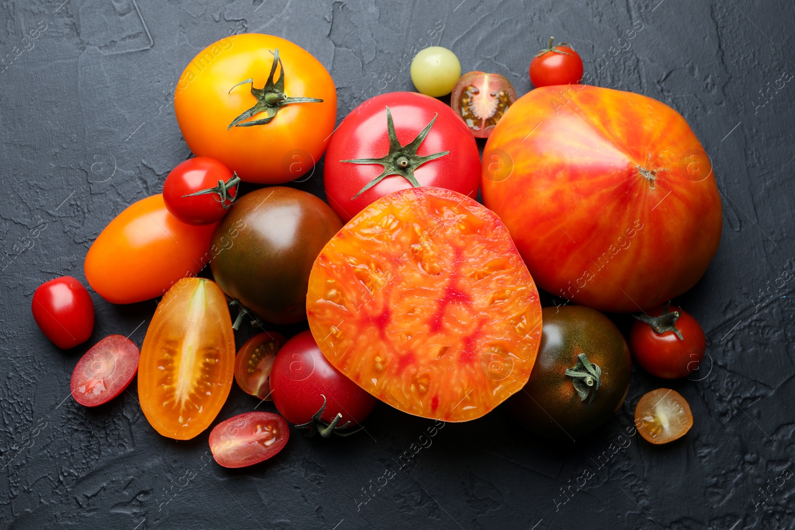 Photo of Different ripe tomatoes on black table, flat lay
