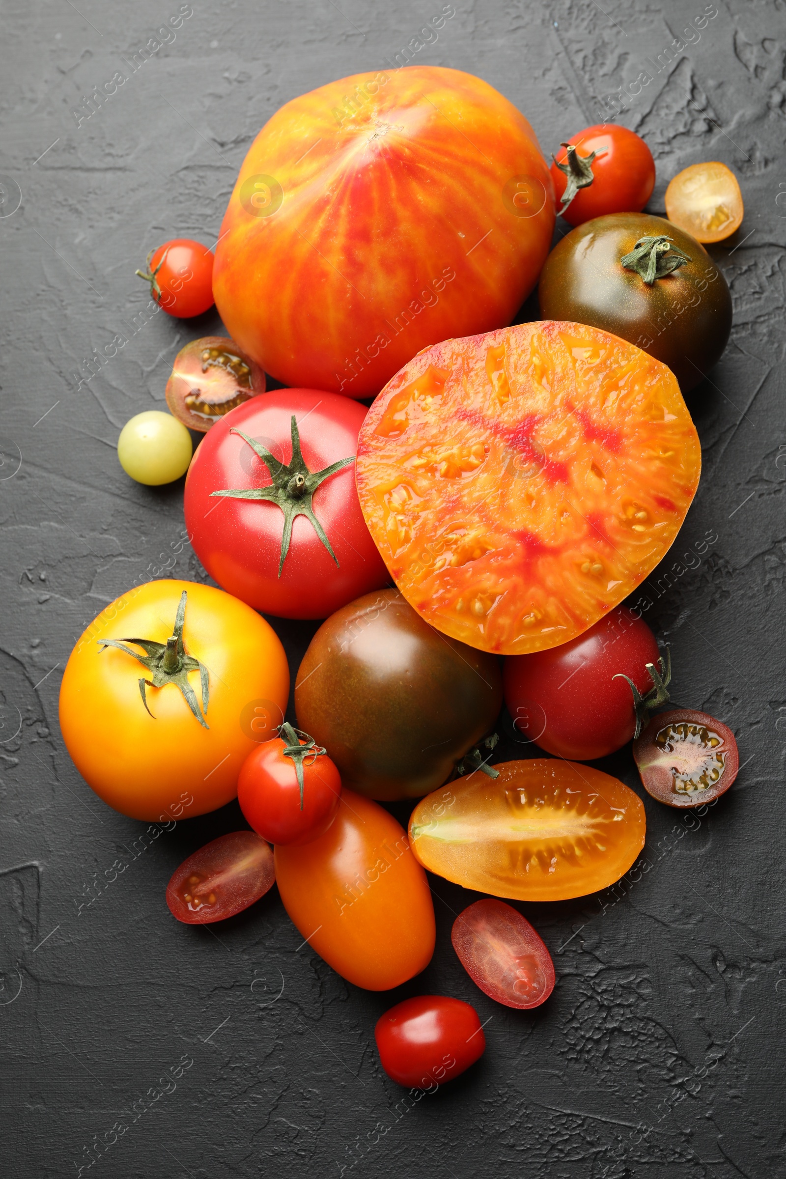 Photo of Different ripe tomatoes on black table, flat lay