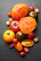Photo of Different ripe tomatoes on black table, flat lay