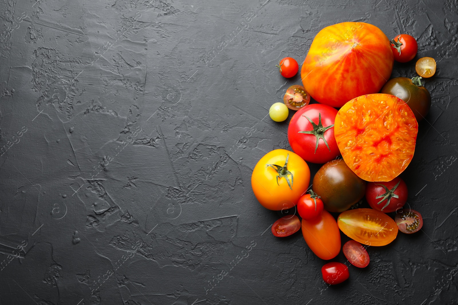 Different ripe tomatoes on black table, flat lay. Space for text Photo of Different ripe tomatoes on black table, flat lay. Space for text