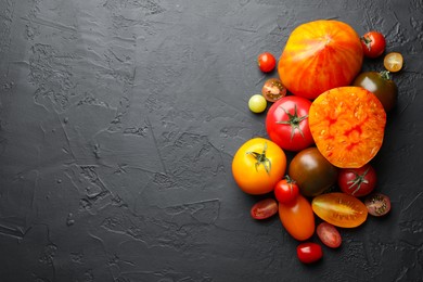 Photo of Different ripe tomatoes on black table, flat lay. Space for text