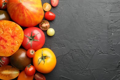 Photo of Different ripe tomatoes on black table, flat lay. Space for text
