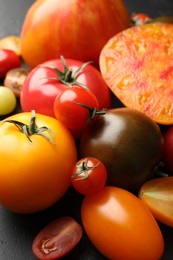 Photo of Different ripe tomatoes on black table, closeup