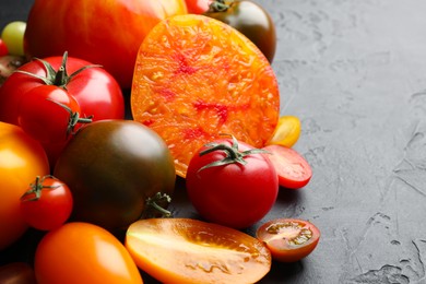 Photo of Different ripe tomatoes on black table, closeup