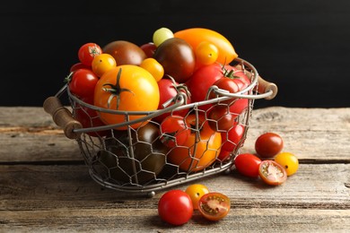 Photo of Different ripe tomatoes in basket on wooden table, closeup