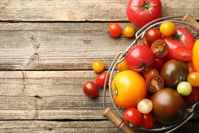 Photo of Different ripe tomatoes in basket on wooden table, top view. Space for text