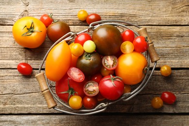 Photo of Different ripe tomatoes in basket on wooden table, top view