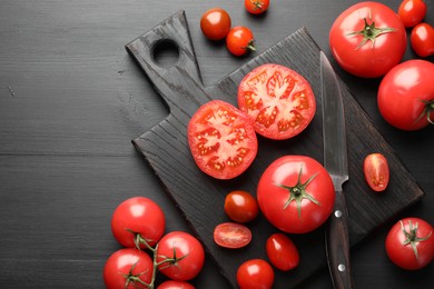 Photo of Whole and cut red tomatoes with knife on black table, flat lay