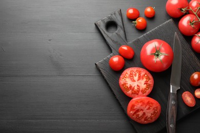 Photo of Whole and cut red tomatoes with knife on black table, flat lay. Space for text