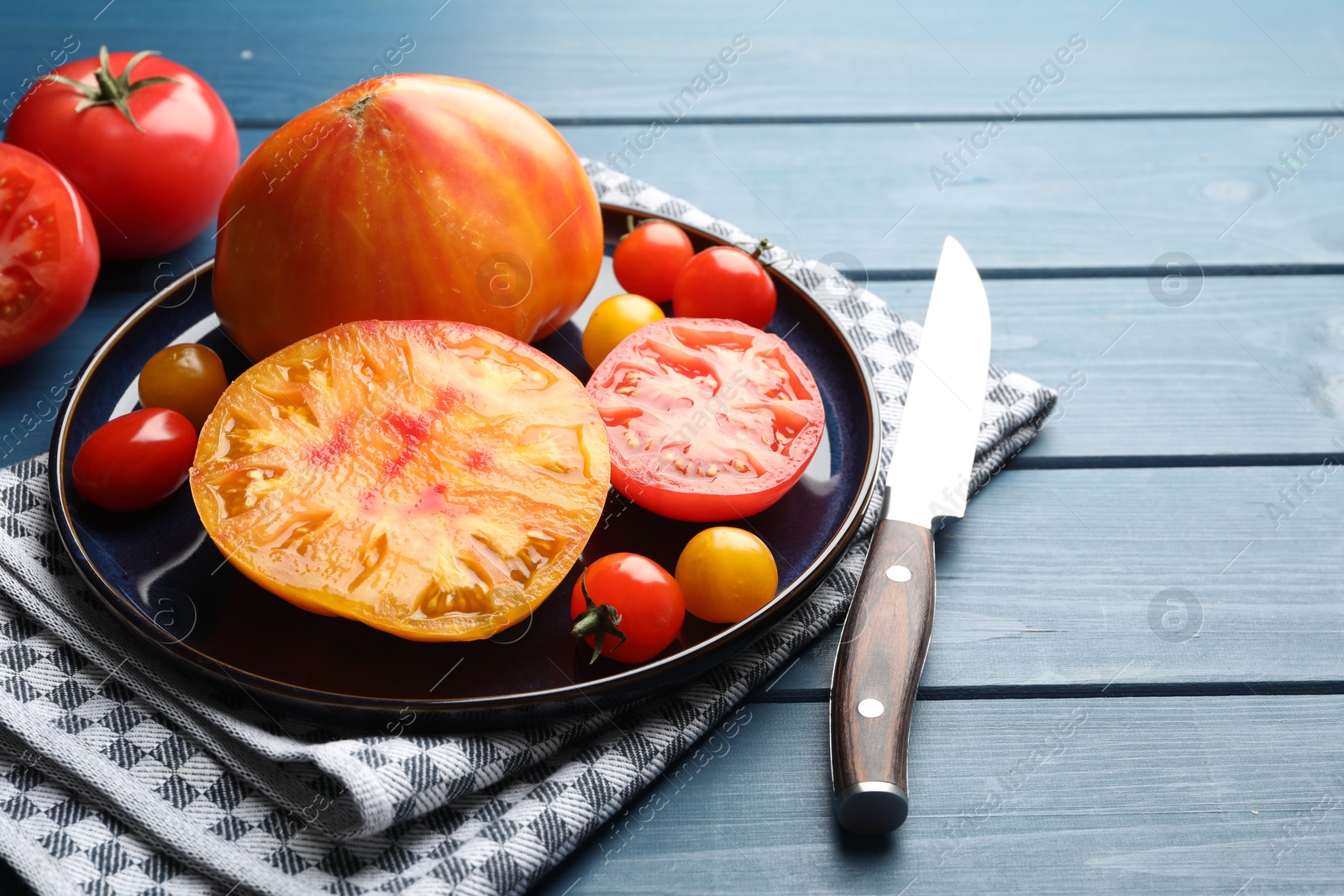 Different ripe tomatoes and knife on blue wooden table, closeup Photo of Different ripe tomatoes and knife on blue wooden table, closeup