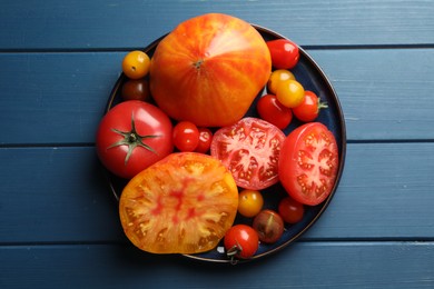 Photo of Different ripe tomatoes on blue wooden table, top view