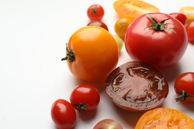 Photo of Different ripe tomatoes on white table, closeup. Space for text