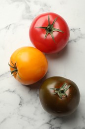 Photo of Different ripe tomatoes on white marble table, flat lay