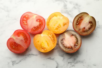 Photo of Pieces of different ripe tomatoes on white marble table, flat lay