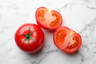 Photo of Whole and cut red tomatoes on white marble table, top view