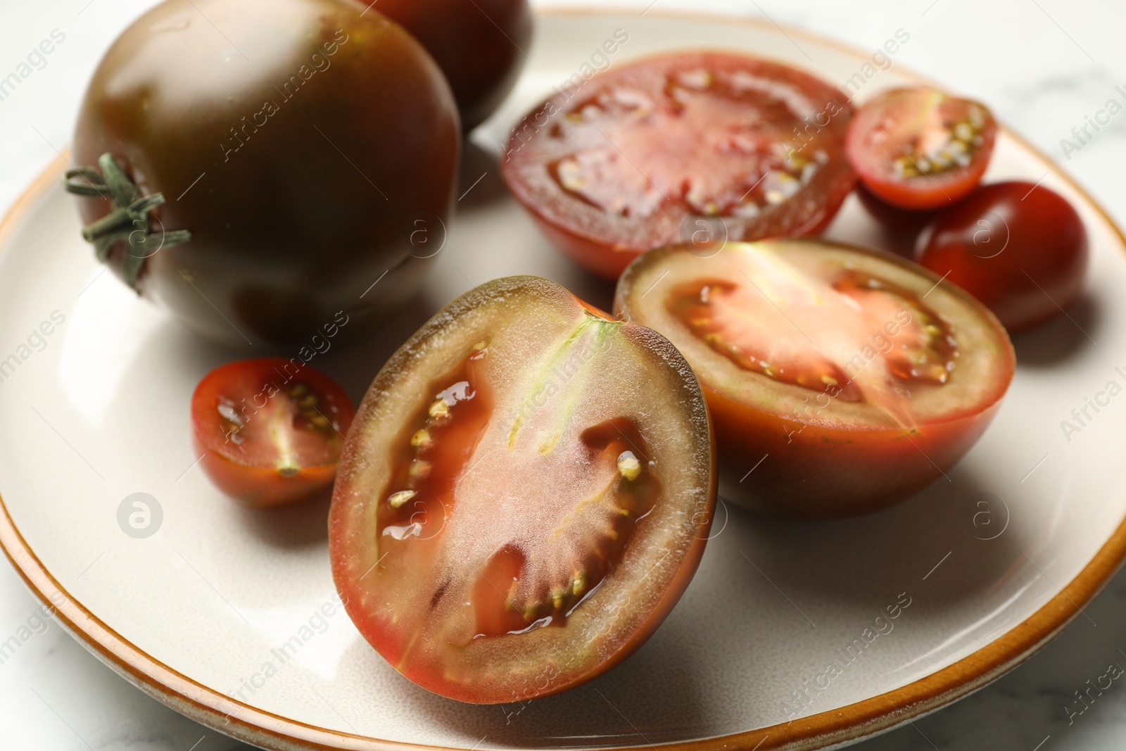 Whole and cut brown tomatoes on white marble table, closeup Photo of Whole and cut brown tomatoes on white marble table, closeup