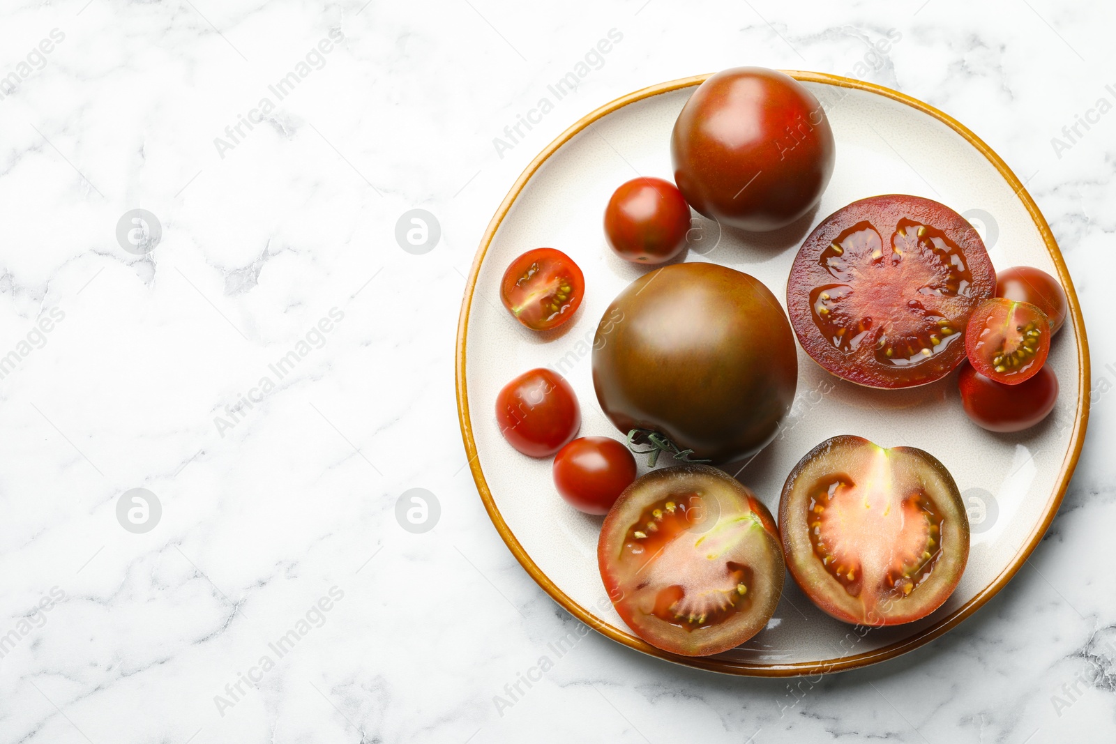 Whole and cut brown tomatoes on white marble table, top view. Space for text Photo of Whole and cut brown tomatoes on white marble table, top view. Space for text