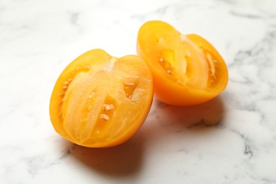 Photo of Pieces of ripe yellow tomato on white marble table, closeup