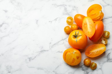 Photo of Whole and cut yellow tomatoes on white marble table, flat lay. Space for text