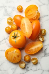 Photo of Whole and cut yellow tomatoes on white marble table, flat lay