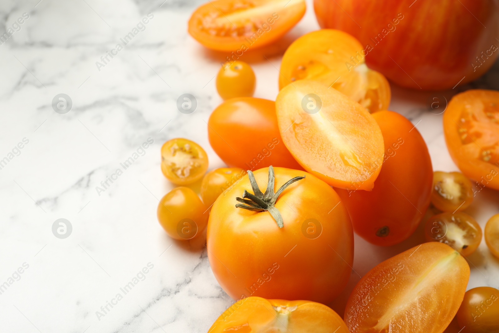 Whole and cut yellow tomatoes on white marble table, closeup. Space for text Photo of Whole and cut yellow tomatoes on white marble table, closeup. Space for text