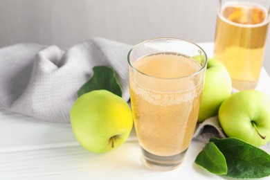 Photo of Fresh cider in glass, bottle and apples on white wooden table, closeup