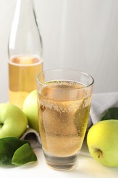 Photo of Fresh cider in glass, bottle and apples on white wooden table, closeup