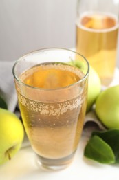 Photo of Fresh cider in glass, bottle and apples on white table, closeup