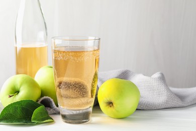 Photo of Fresh cider in glass, bottle and apples on white wooden table