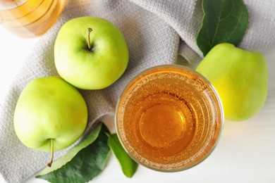Photo of Fresh cider in glass and apples on white table, flat lay
