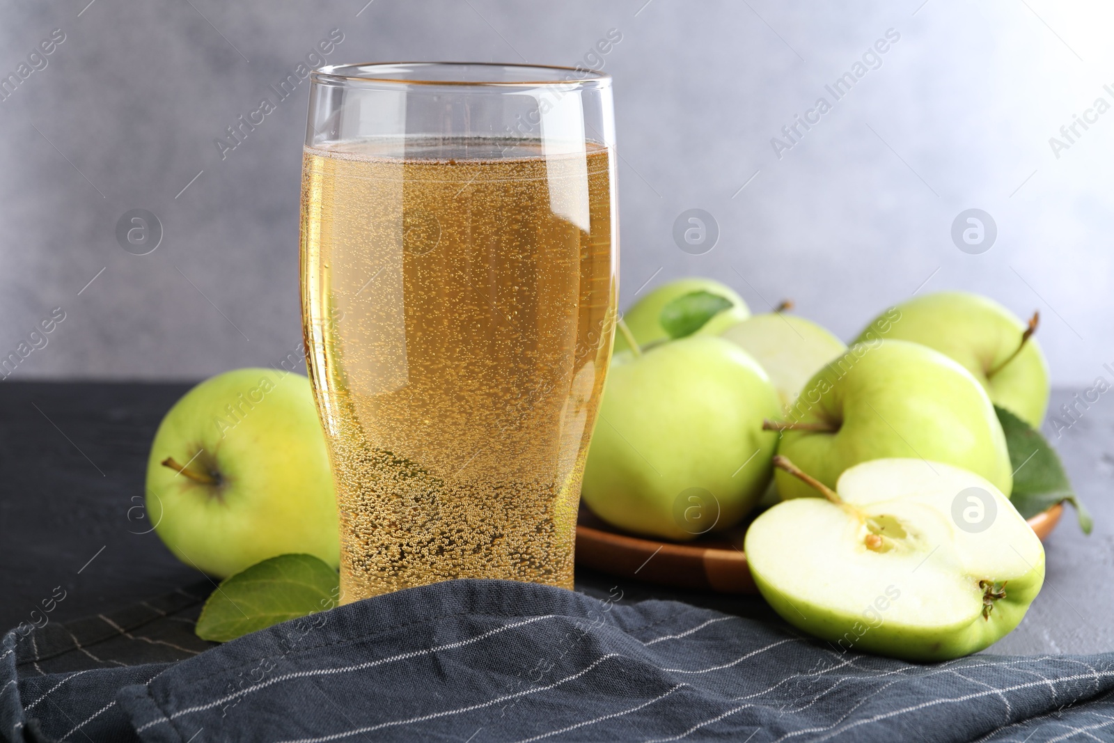 Fresh cider in glass and apples on black table, closeup Photo of Fresh cider in glass and apples on black table, closeup