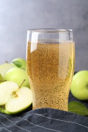 Photo of Fresh cider in glass and apples on table, closeup