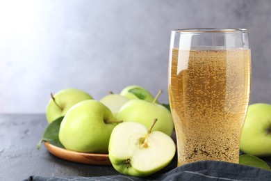 Photo of Fresh cider in glass and apples on black table, closeup