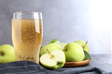 Photo of Fresh cider in glass and apples on black table, closeup