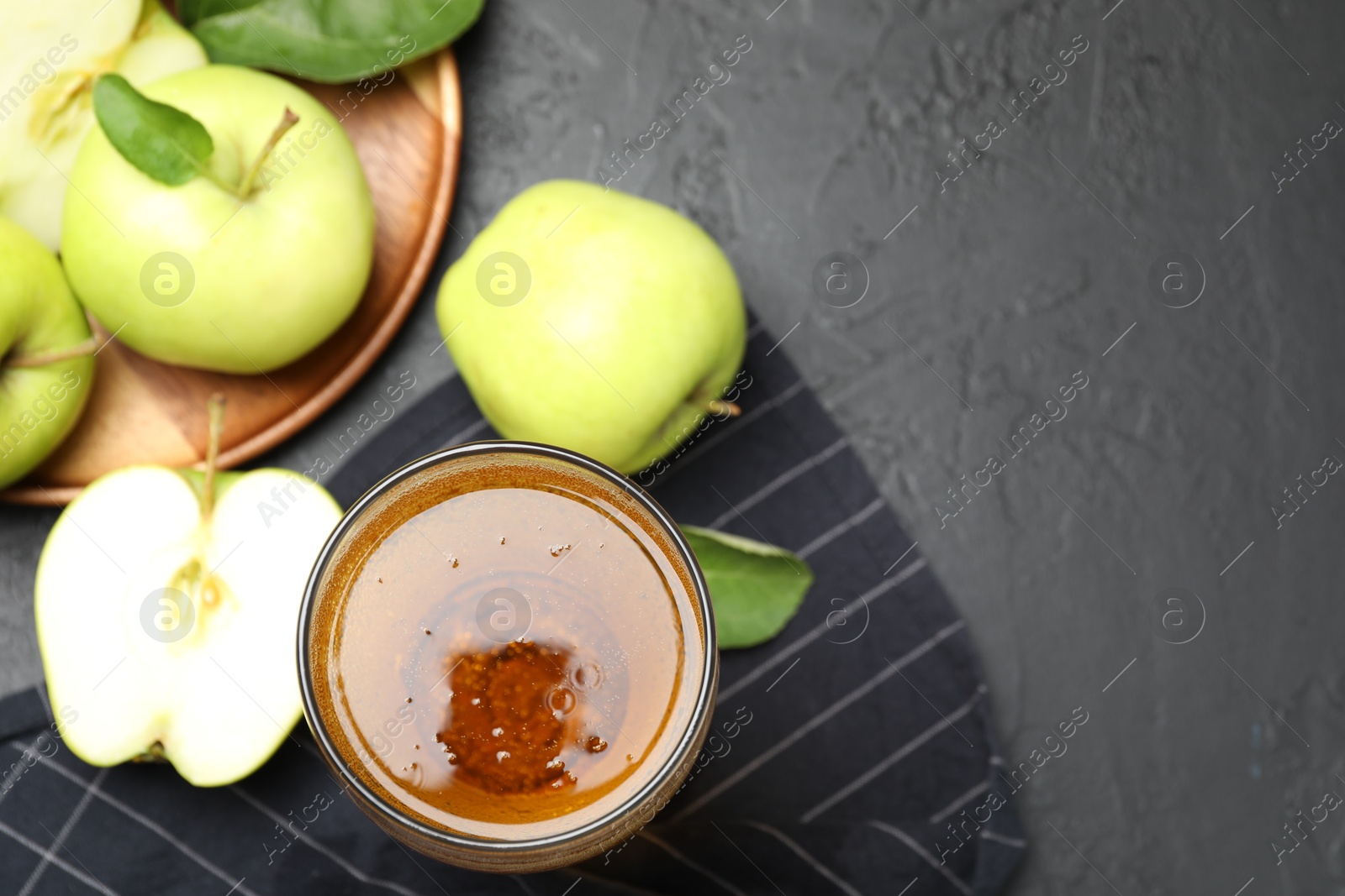 Fresh cider in glass and apples on black table, flat lay. Space for text Photo of Fresh cider in glass and apples on black table, flat lay. Space for text