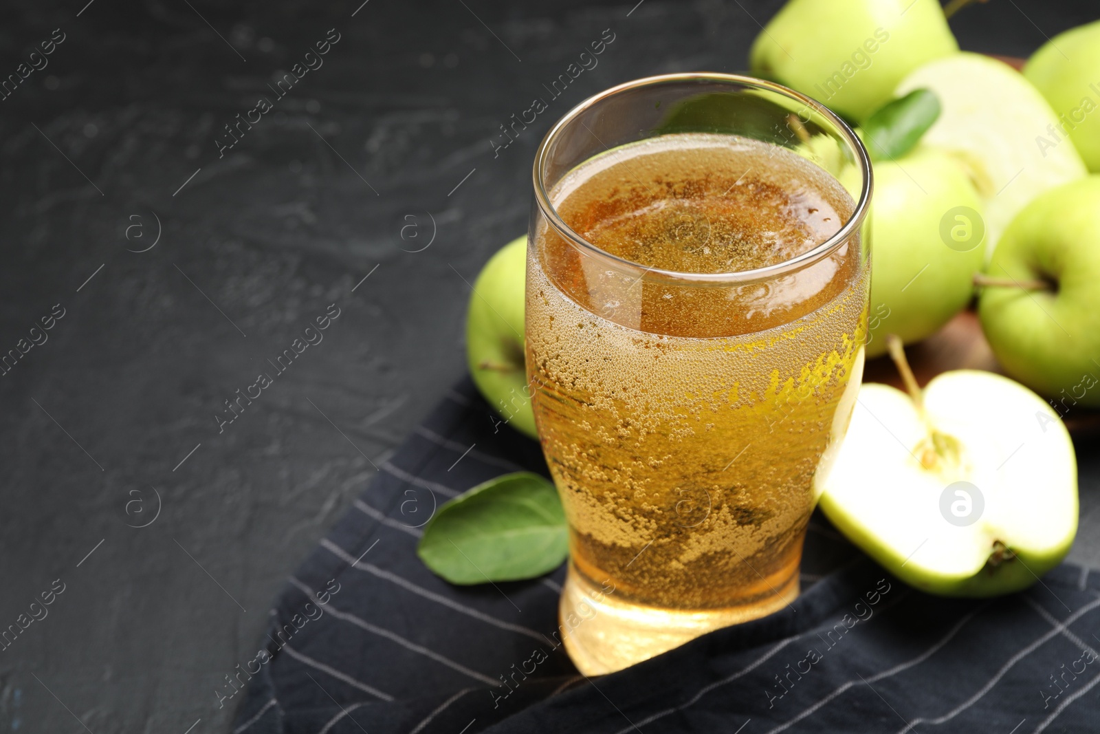 Fresh cider in glass and apples on black table, closeup. Space for text Photo of Fresh cider in glass and apples on black table, closeup. Space for text