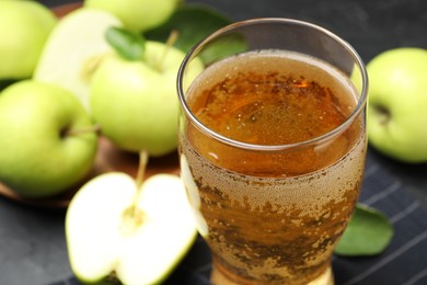 Photo of Fresh cider in glass and apples on table, closeup