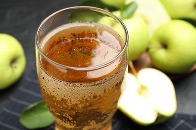 Photo of Fresh cider in glass and apples on table, closeup
